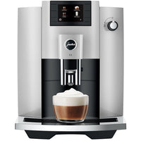 Jura E6 Espresso Machine with TFT display and cappuccino in a glass, showcasing fine foam technology.